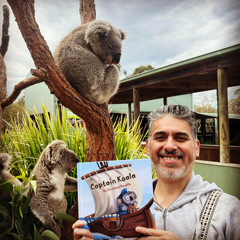 Christian Ravello holding his Captain Koala children’s book beside two koalas